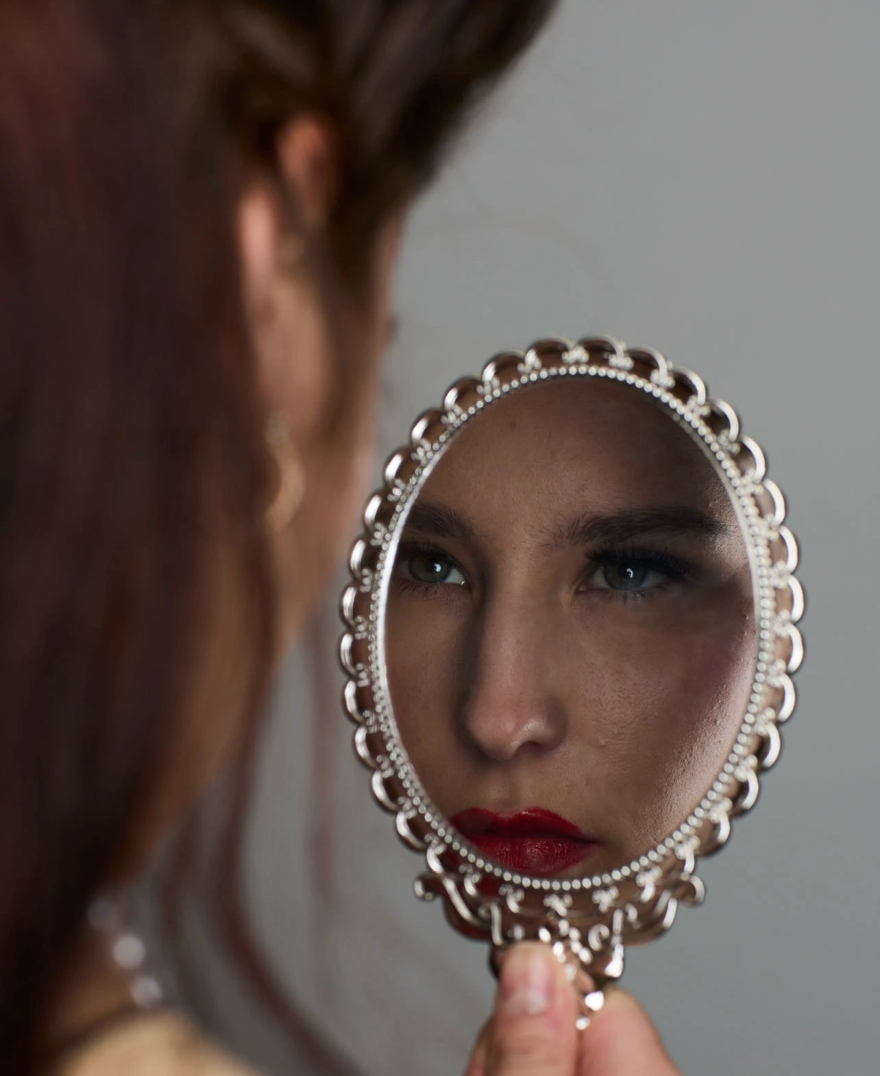 Event makeup reflected in a hand mirror